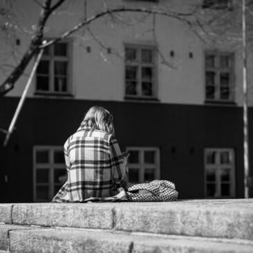 Yksinäisyyttä kuvastava kuvituskuva. Nuori selkä kameraan päin, istu kiviportailla.