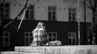 Yksinäisyyttä kuvastava kuvituskuva. Nuori selkä kameraan päin, istu kiviportailla.